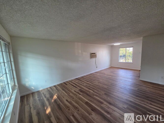 A room with wooden flooring and a window on the left side.