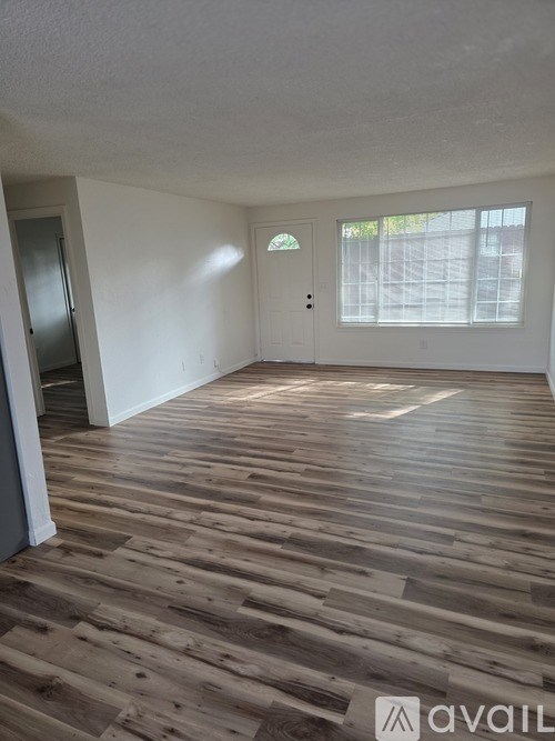 A room with wooden flooring and a door leading to a balcony.