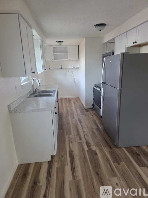 A kitchen with a refrigerator, sink, and cabinets.