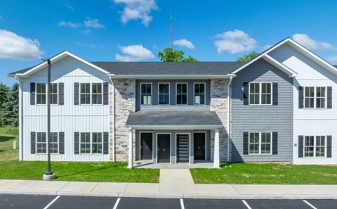 A modern two-story building with a stone facade and a grey roof.