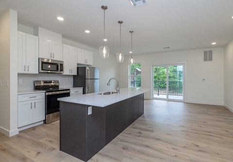 A modern kitchen with a large island and wooden floors.