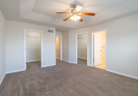 A room with a ceiling fan and carpeted floor.