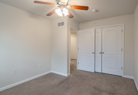 A room with a ceiling fan and two doors.