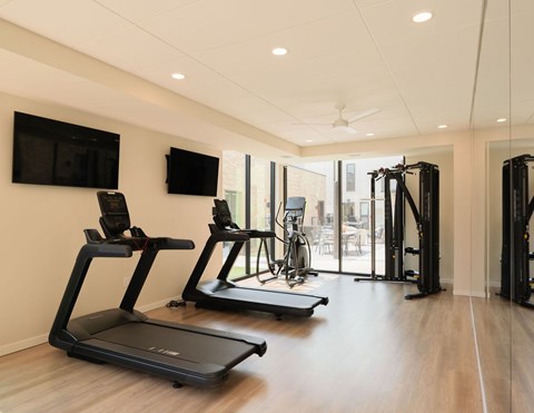 A gym with treadmills, a stationary bike, and a television.