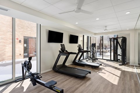 A gym with treadmills, exercise bikes, and a television.