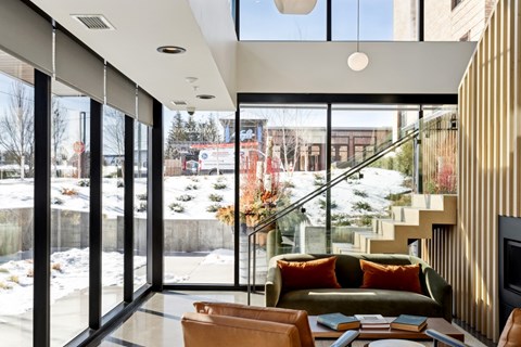 A modern living room with a glass wall and a view of the outdoors.