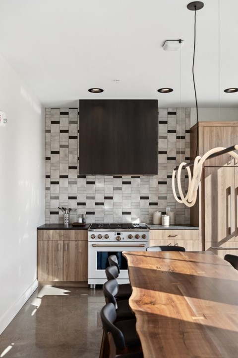A modern kitchen with a white stove top oven and a black backsplash.