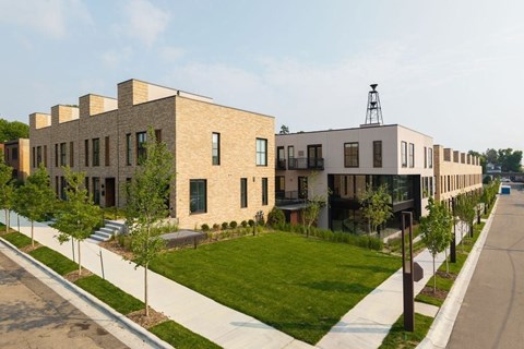 A long row of modern houses with a grassy area in between.