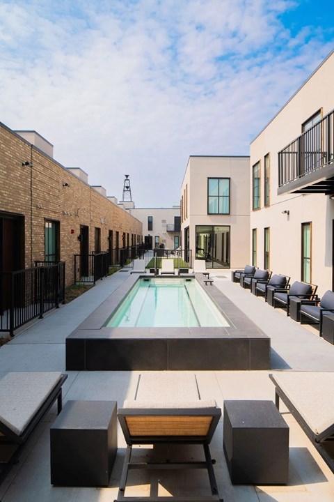 A pool surrounded by black and white furniture.