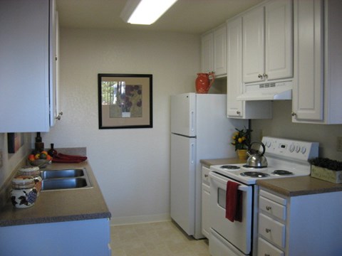 A kitchen with white appliances and cabinets.