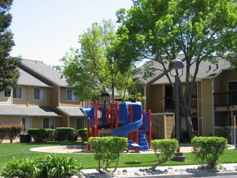 A playground with a blue slide in front of a building.