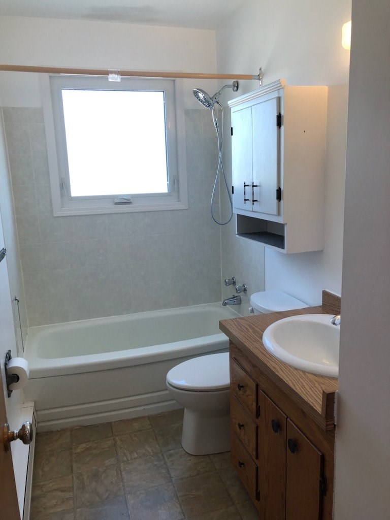 A white toilet sits next to a bathtub in a bathroom.