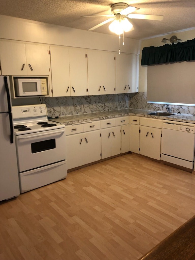 A kitchen with white appliances and wooden floors.