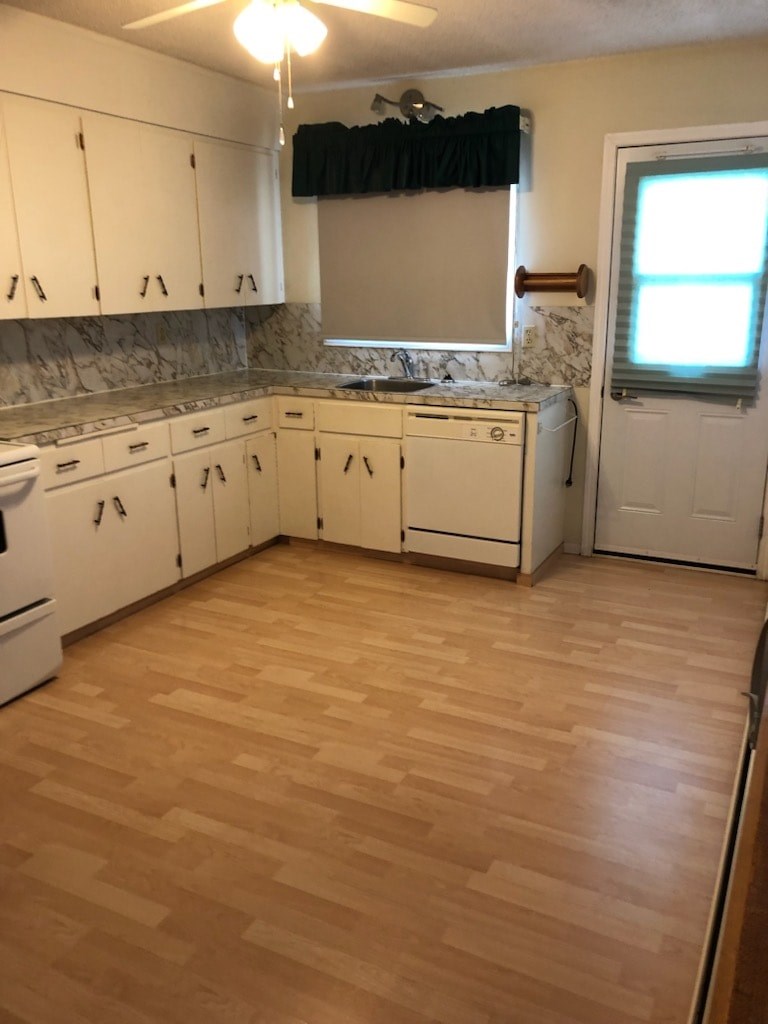 A kitchen with white appliances and wooden floors.