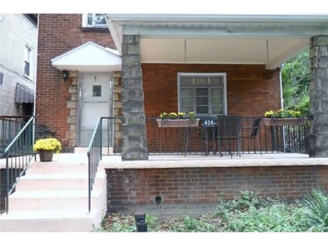 A red brick house with a white door and a small porch.