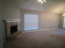 A room with a fireplace and a window with blinds.