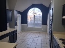 A kitchen with black cabinets and a white counter.