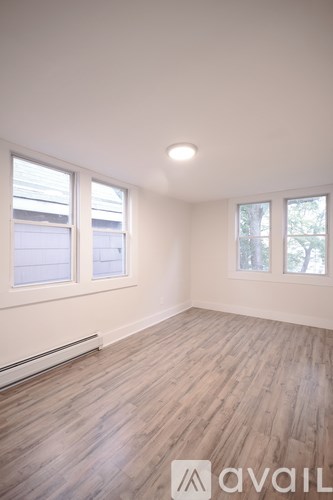 A room with wooden flooring and two windows.