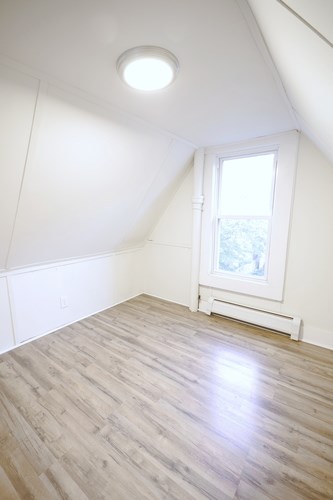 A room with a window and a white radiator on the floor.