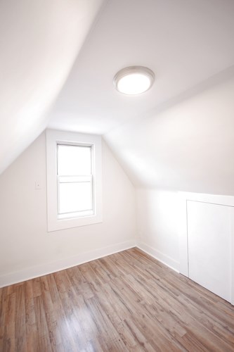 A room with a window and wooden flooring.