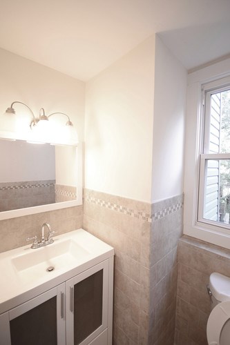 A bathroom with a toilet, sink, and mirror.