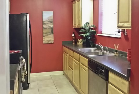 A kitchen with red walls and a black refrigerator.