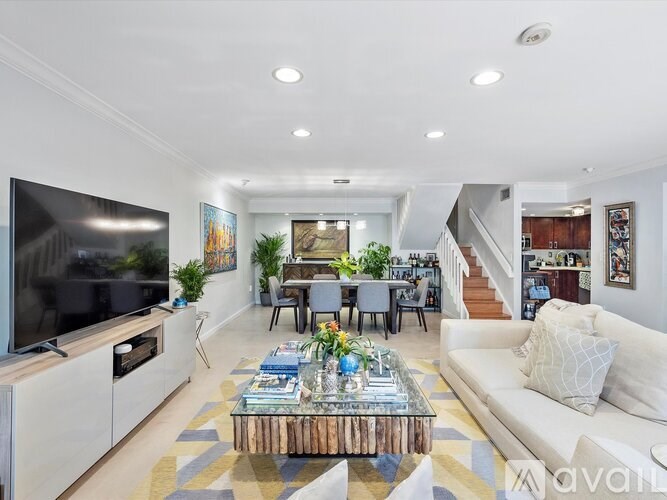 A modern living room with a white sofa, a wooden coffee table, and a flat-screen TV.