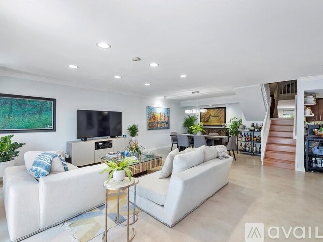 A living room with a white couch, a coffee table, and a staircase in the background.