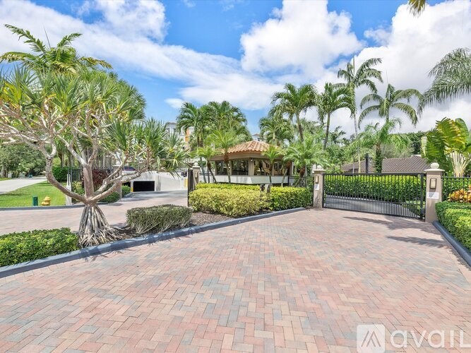 A driveway leads to a house with a gate and a palm tree.
