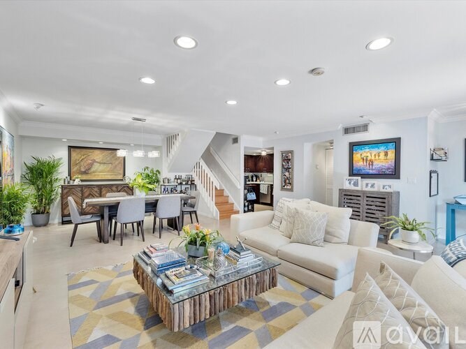 A living room with a white couch, a coffee table, and a painting on the wall.