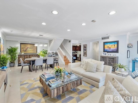 A living room with a white couch, a coffee table, and a painting on the wall.