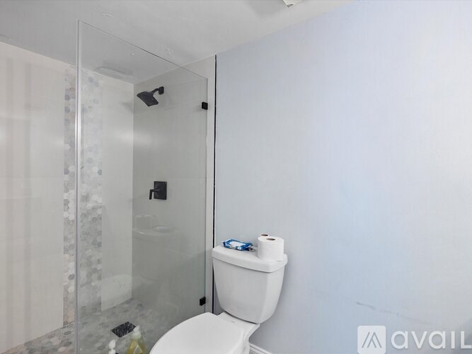 A white toilet with a roll of toilet paper on top of it.