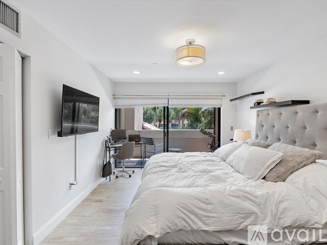 A bedroom with a large bed and a flat screen TV mounted on the wall.