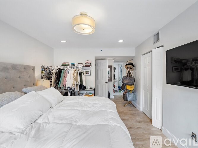 A bedroom with a large bed and a closet full of clothes.
