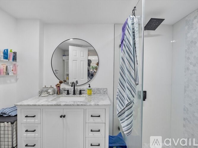 A bathroom with a white cabinet and a round mirror.