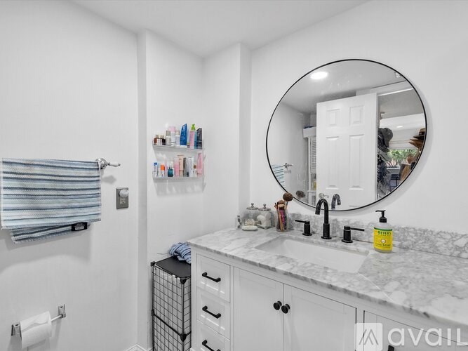A bathroom with a marble countertop and a round mirror.