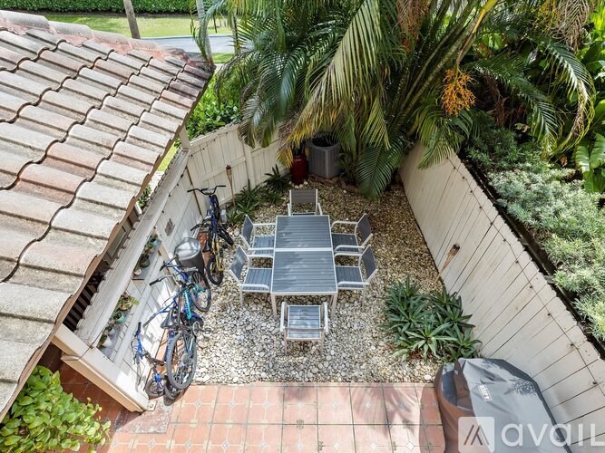 A patio with a table and chairs surrounded by plants.