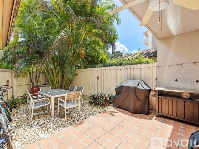 A patio with a table and chairs surrounded by a fence and trees.