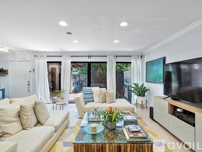 A living room with a white couch, a glass coffee table, and a flat screen TV.