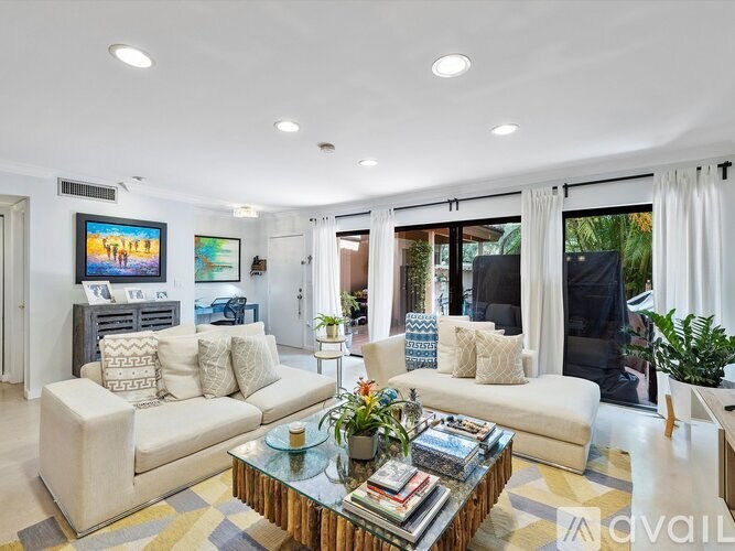 A living room with a white couch, a coffee table, and a flat-screen TV mounted on the wall.