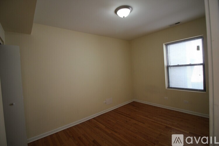 A room with wooden floors and a window with blinds.