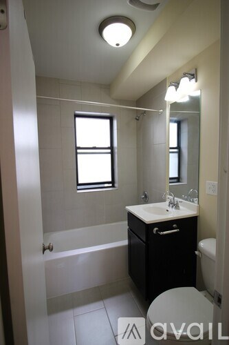 A bathroom with a white sink and a black cabinet.