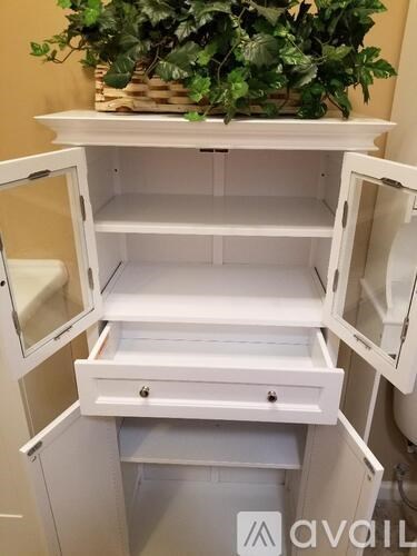 A white cabinet with a drawer is open.