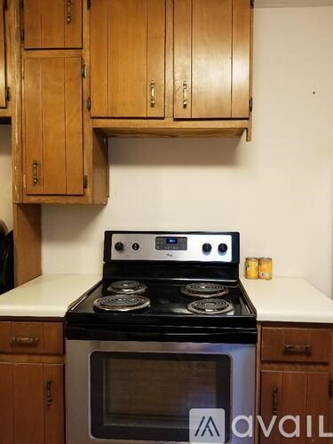 A black and silver stove with a digital display is in a kitchen with wooden cabinets.