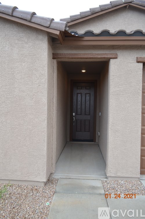 A house entrance with a dark brown door and a concrete walkway.