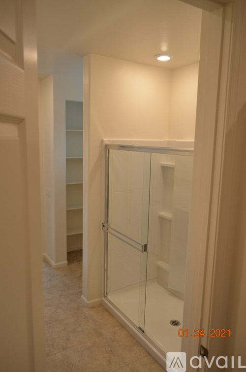 A bathroom with a walk-in shower and a glass door.