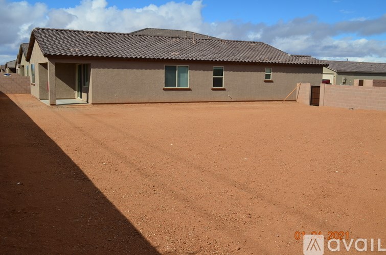 A building with a brown roof and a brown dirt ground in front of it.