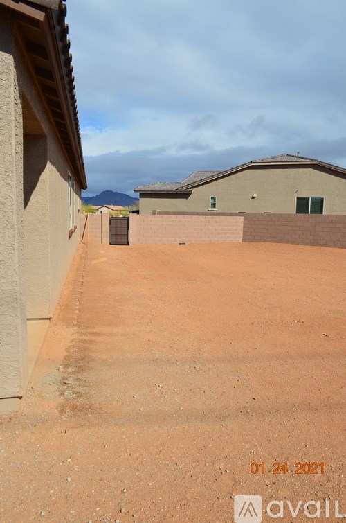 A dirt path leads to a building with a mountain in the background.