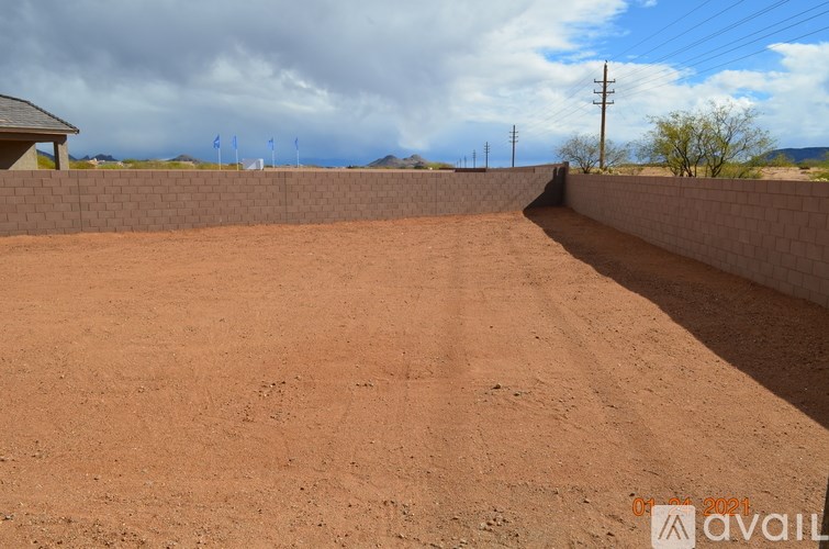 A dirt field with a wall and power lines in the distance.