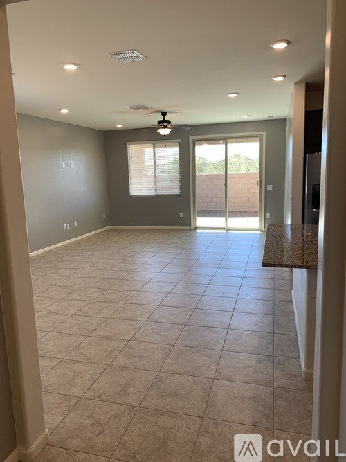 A spacious room with tile flooring and a ceiling fan.